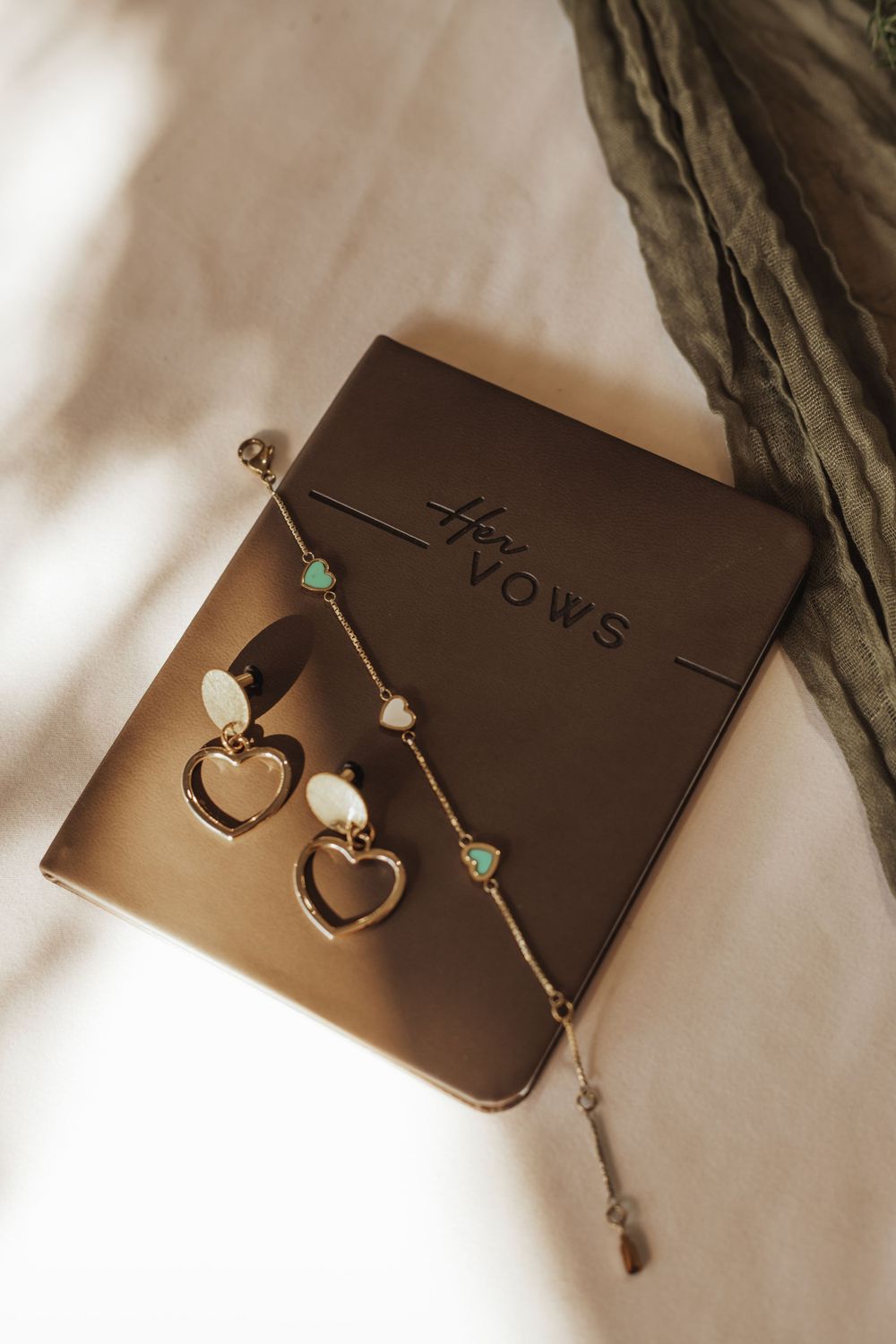 Delicate pearl and heart-shaped earrings displayed on a brown surface in natural lighting.