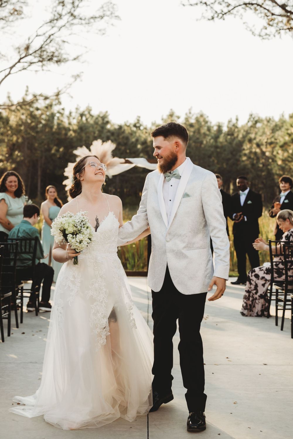 A romantic wedding moment captured outdoors with a white gown and formal attire against a natural backdrop.