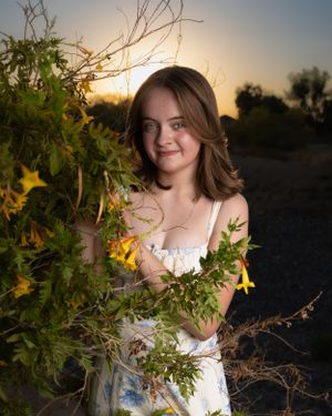 Dreamy sunset portrait amidst yellow wildflowers and natural foliage.