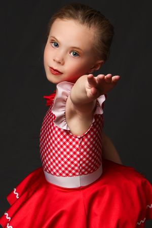 Dance portrait in red and white gingham dress against dark background with dramatic pose.