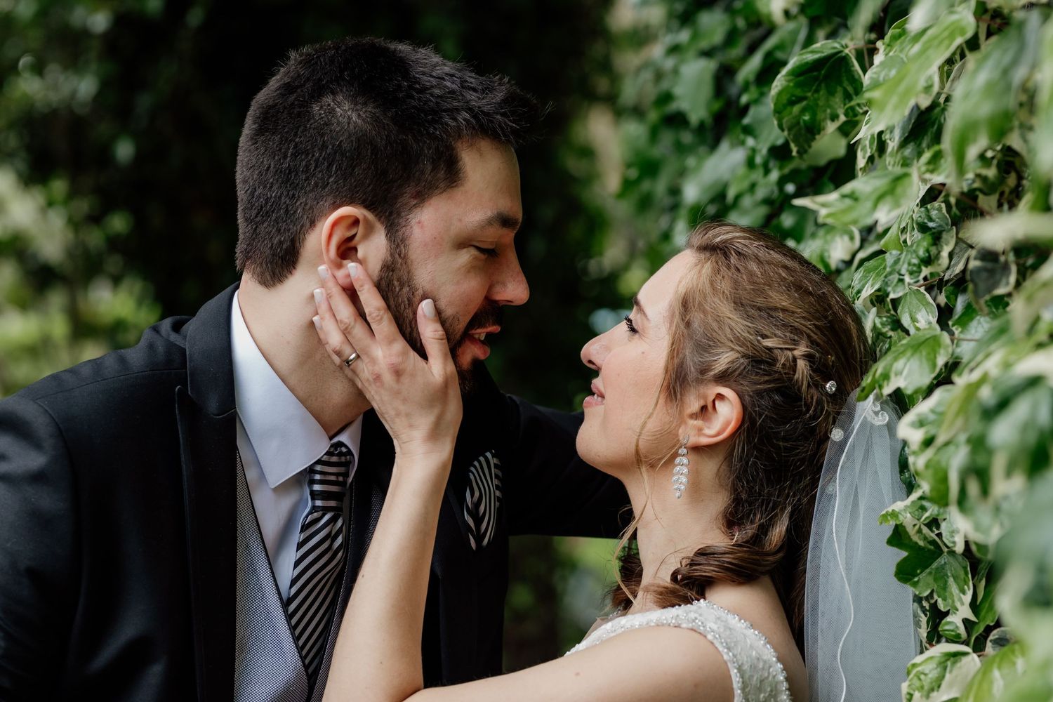 Intimate wedding portrait with couple amid lush green foliage.