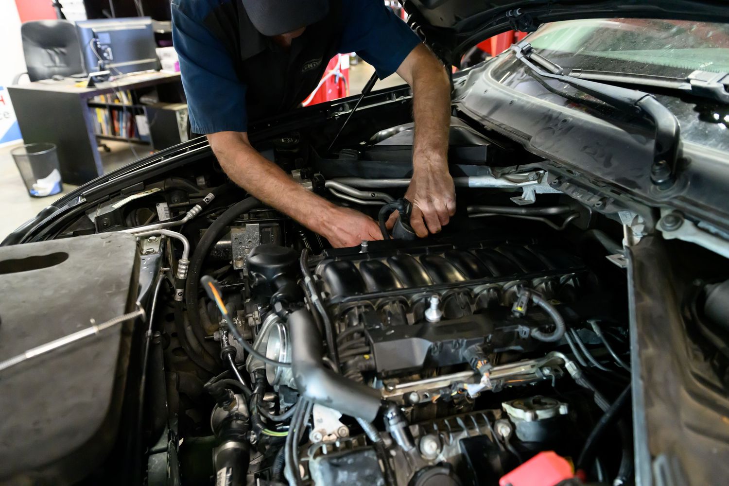 Mechanic working on car engine maintenance in auto repair shop.