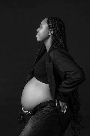 Black and white maternity photo featuring stylish mom-to-be with long braids.