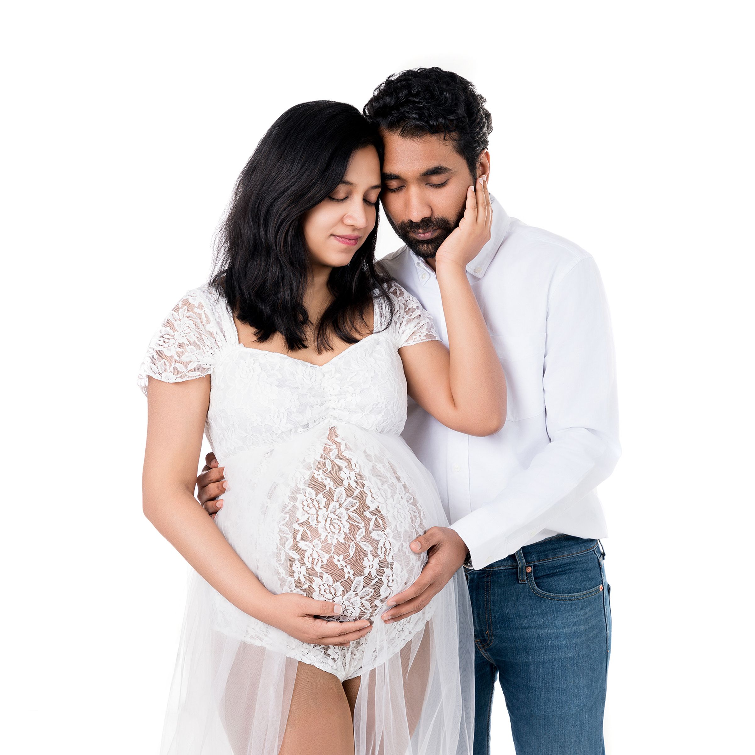 Intimate maternity portrait of couple in white lace against white background.
