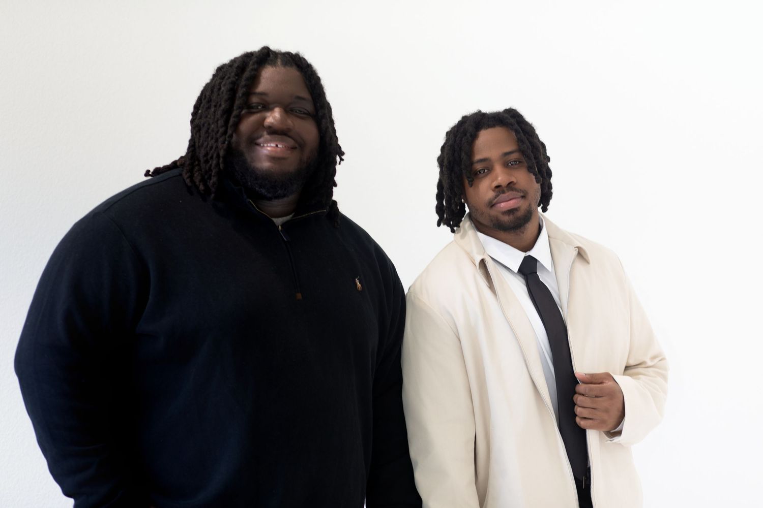 Two men in contrasting outfits posing against white background for professional portrait.
