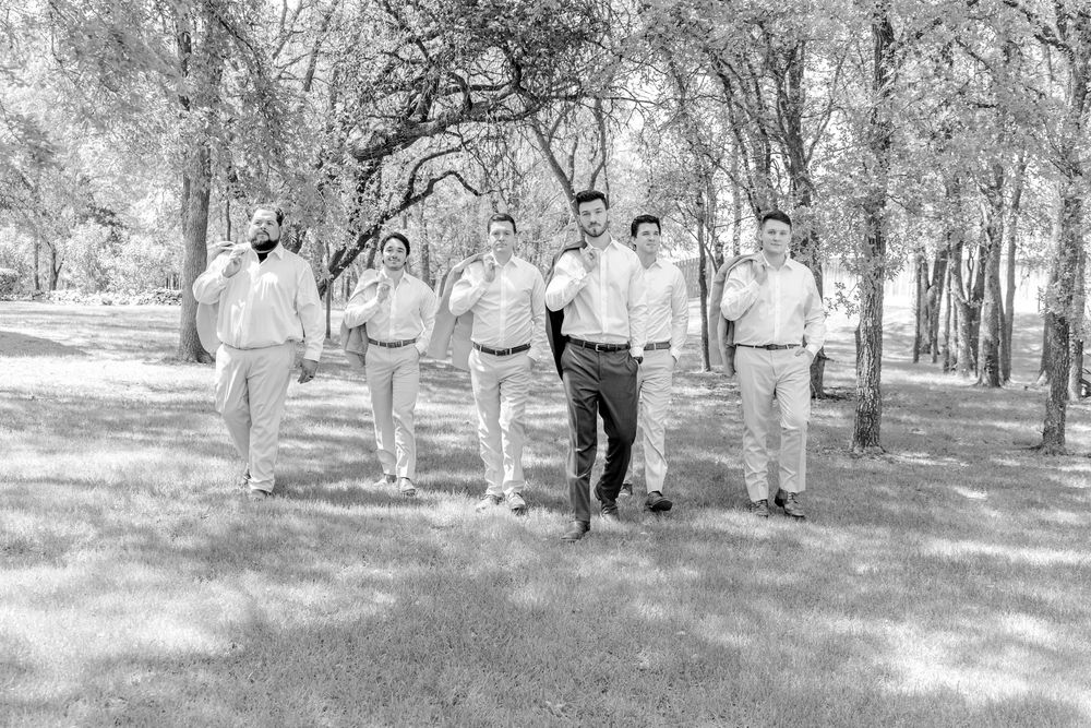 Black and white photo of a group of people walking together in casual attire through a tree-lined park.