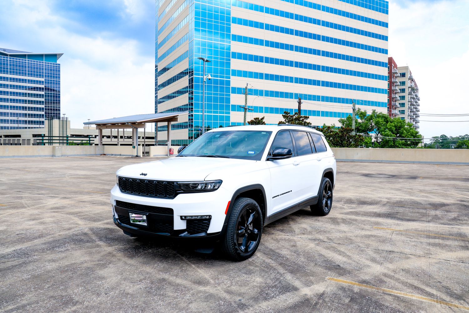 White Jeep Grand Cherokee shown from multiple angles in a parking lot with modern office buildings in the background.