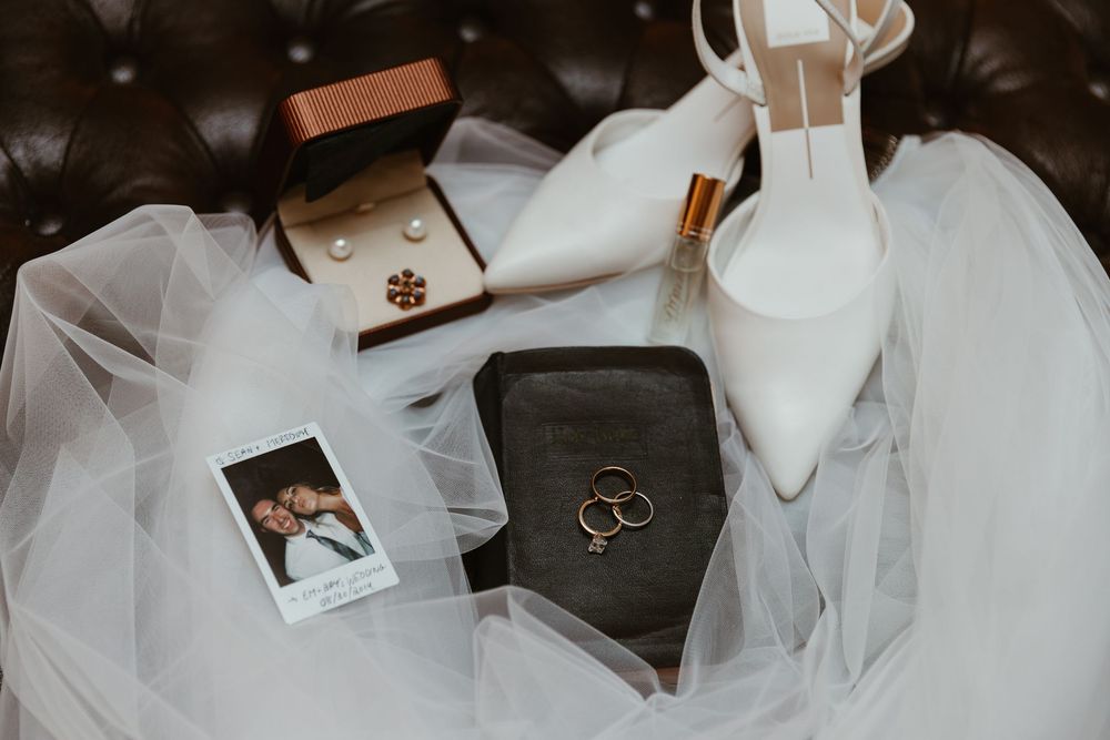 Wedding accessories including rings and Bible draped with flowing white tulle fabric.