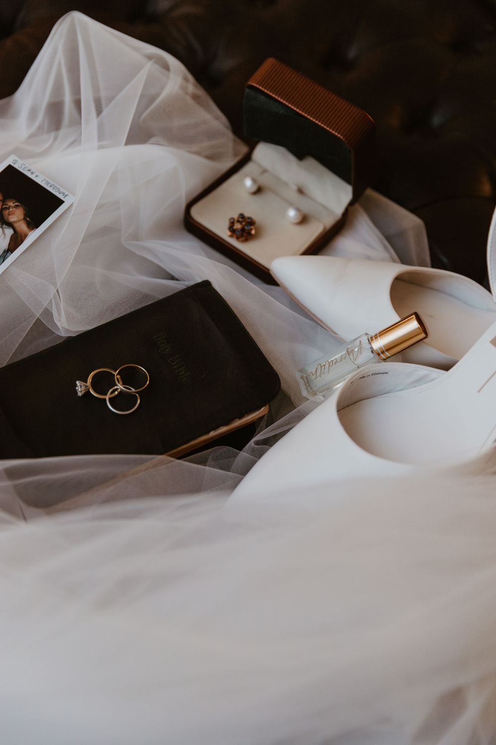 Wedding rings and accessories styled with flowing white fabric in dramatic lighting.