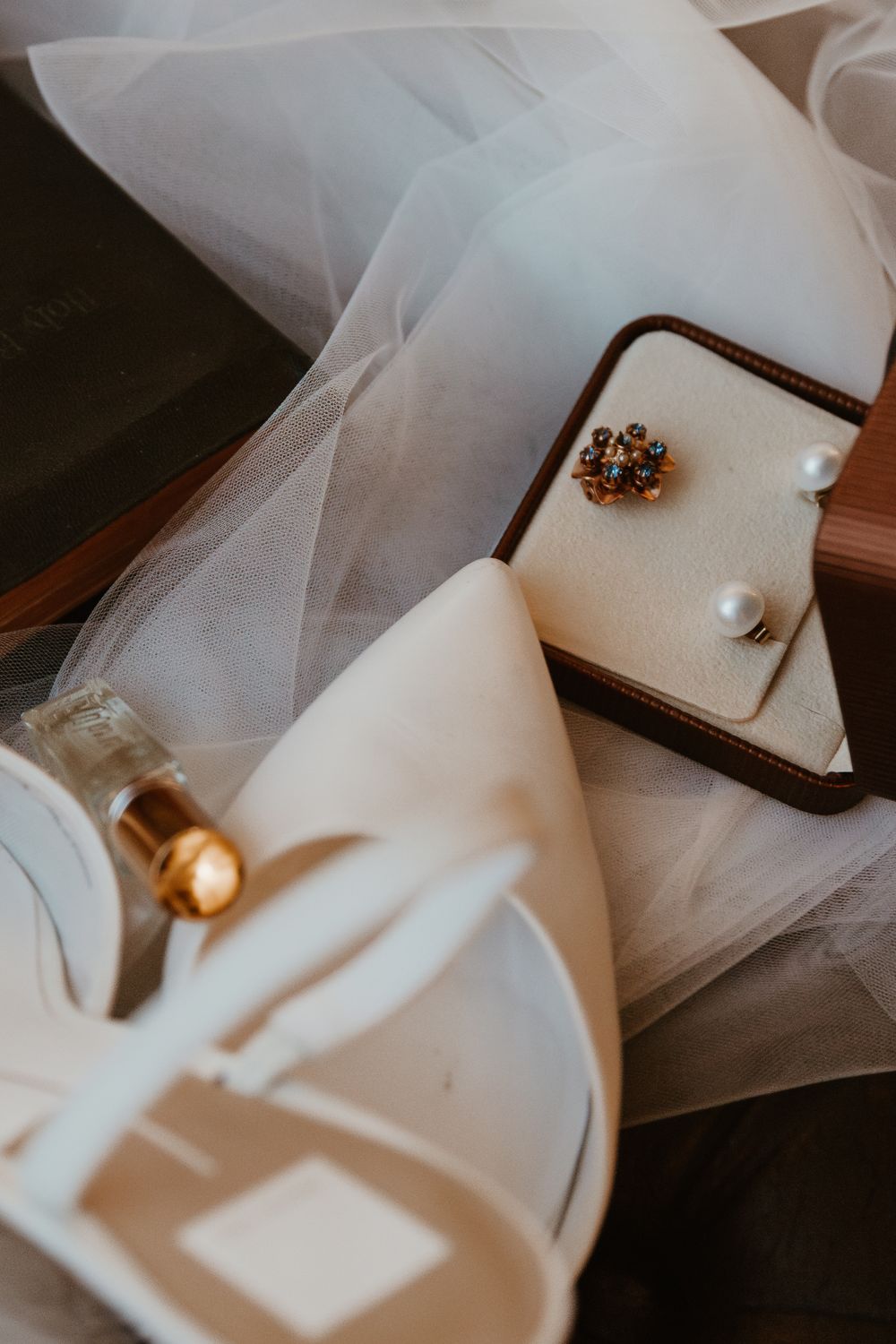 Wedding accessories and jewelry arranged with white tulle in soft lighting.