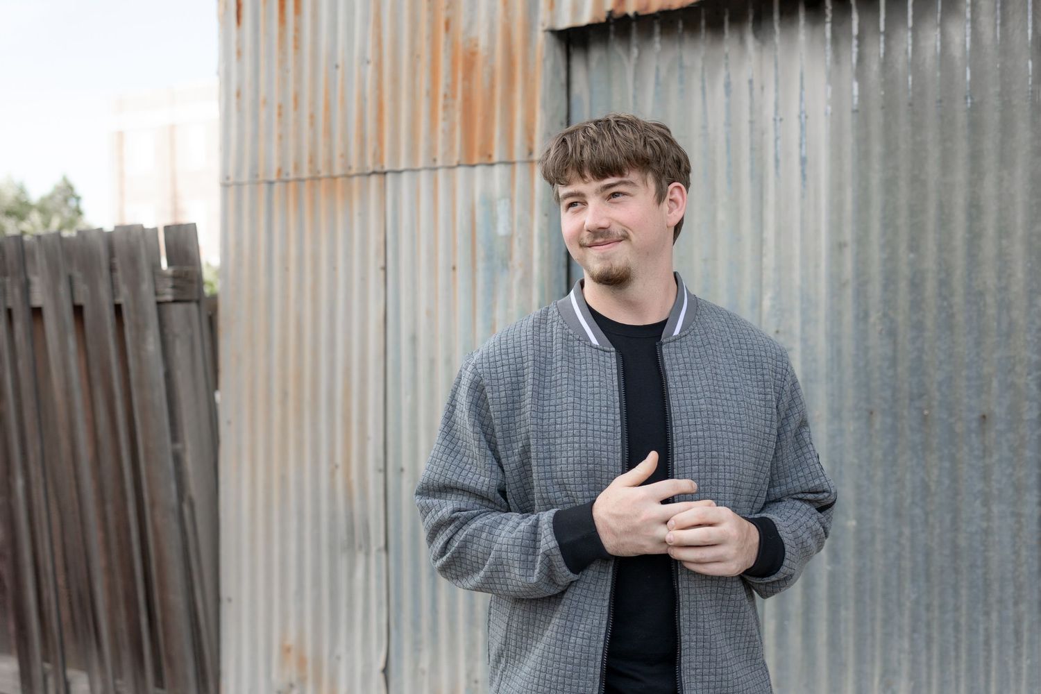 Senior boy standing by a corrugated wall with relaxed pose, warehouse setting