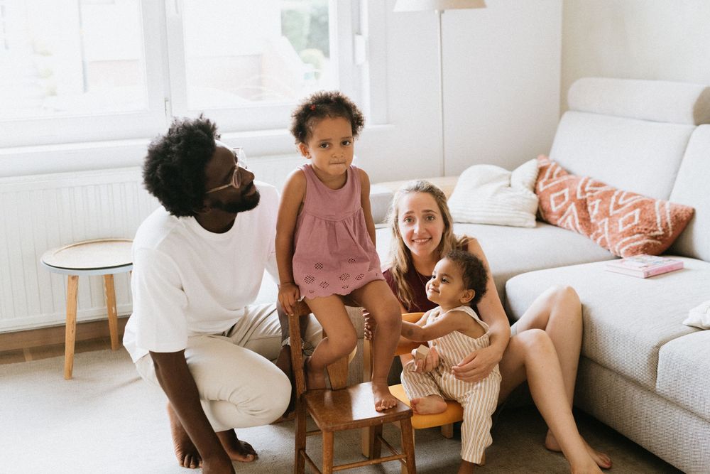 Parents and child relax on couch enjoying quality family time together in bright modern living room.