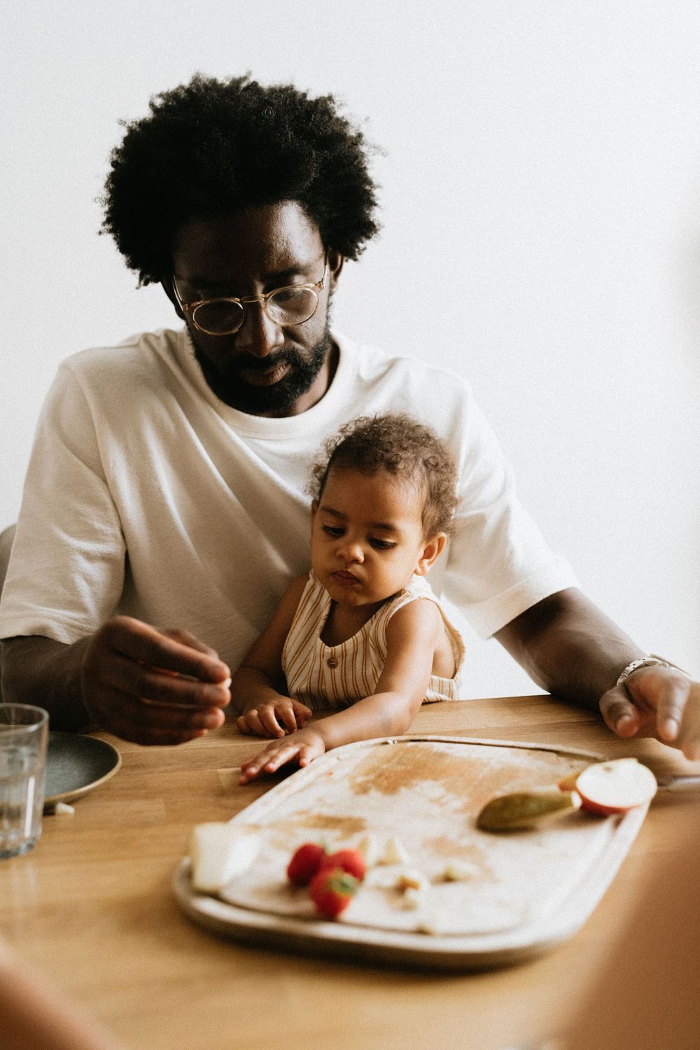 A parent and child share a meal together at a wooden table with a cozy warm atmosphere.
