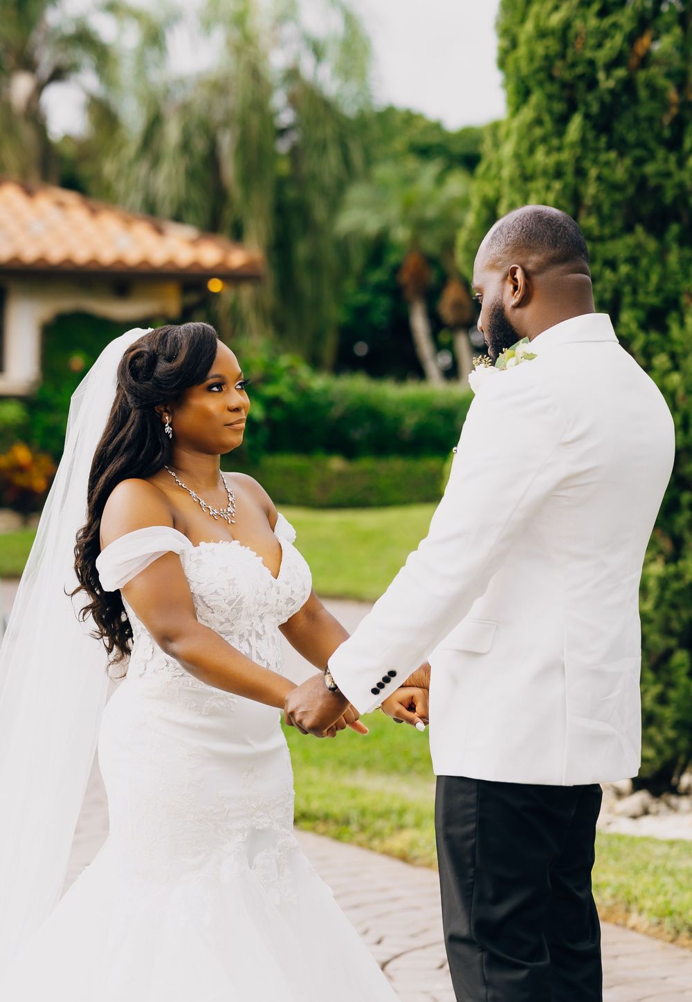 A couple shares an intimate moment during their outdoor garden wedding ceremony wearing elegant white attire.