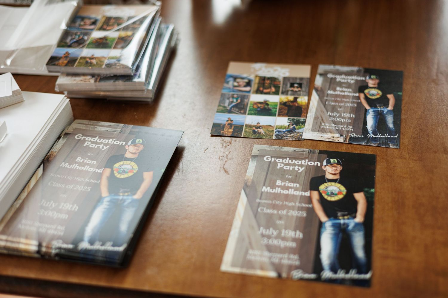 Wedding invitation cards and photo albums arranged on a wooden table showing event photography and details.
