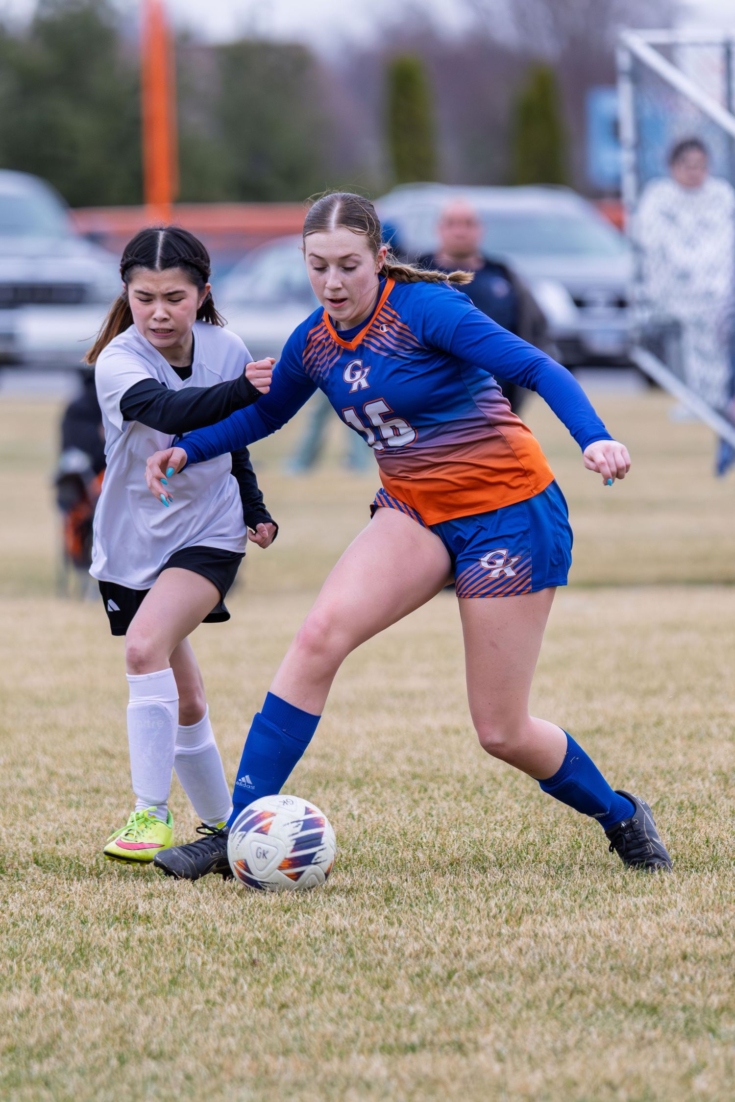 Soccer players compete for ball control during match on grass field.
