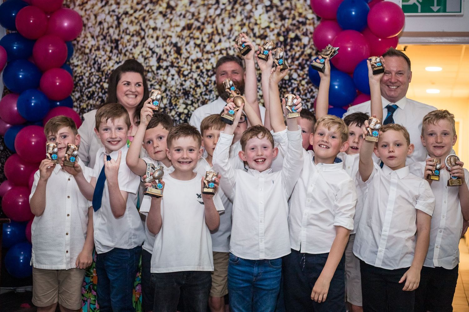 Group photo of young rugby players at Awards Night smiling and holding small trophies