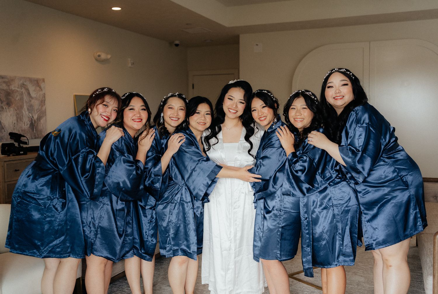 A group wearing matching navy blue robes poses together during a wedding preparation moment.