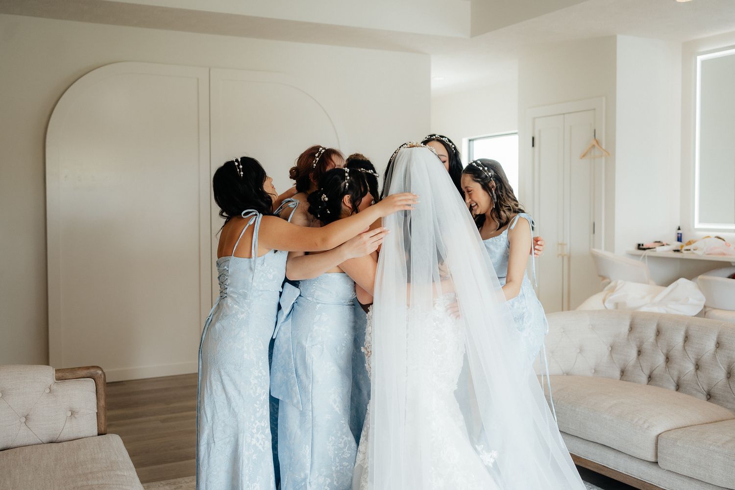 Bridesmaids in light blue dresses hugging in a circle.