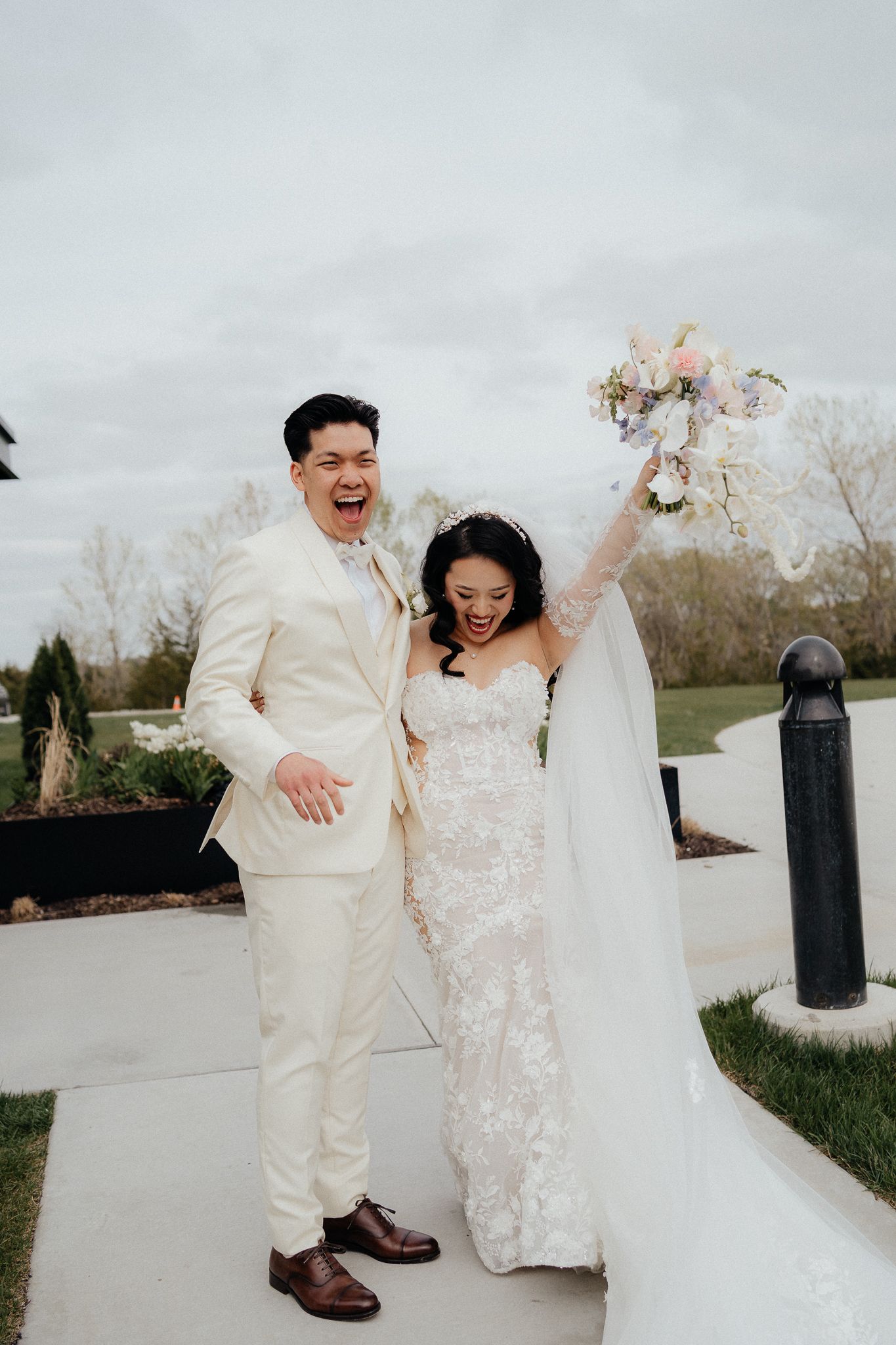 Joyful newlyweds celebrate on their wedding day with the bride raising her bouquet in triumph.