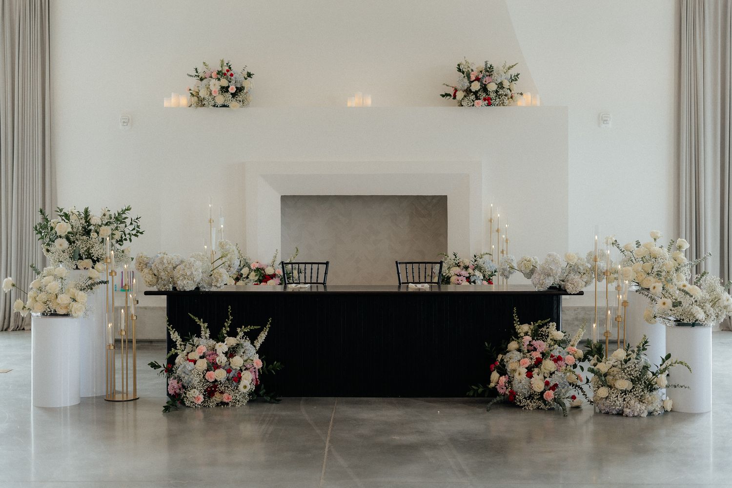 An elegant wedding reception head table setup with black tablecloth and white floral arrangements.