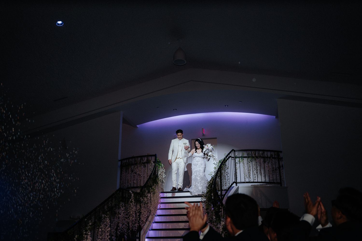 Dramatic nighttime entrance of couple descending illuminated staircase.