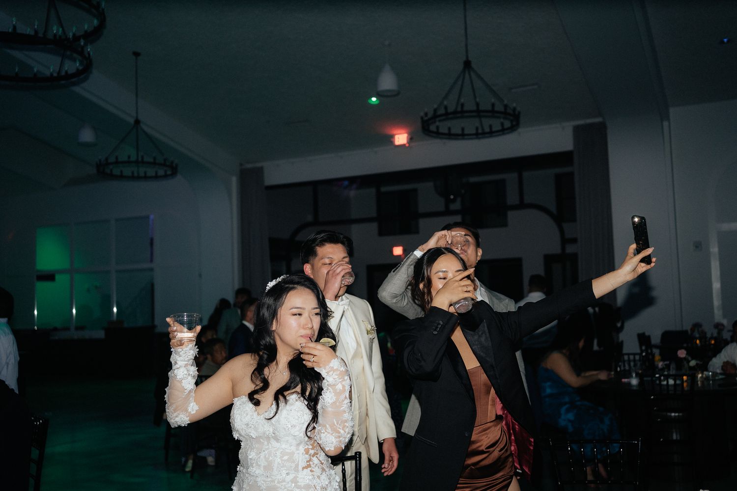 People dance energetically at a nighttime party venue with green ambient lighting in the background.