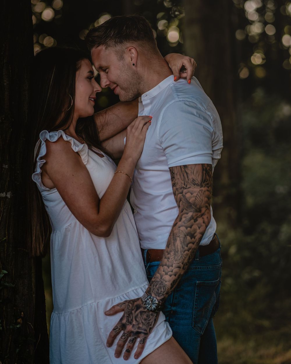 Intimate couple's portrait with soft bokeh lighting and rustic backdrop.