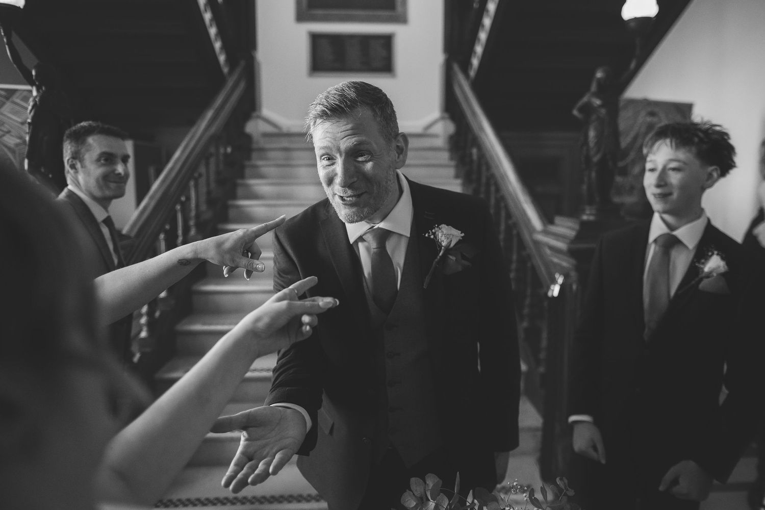 A black and white candid photograph of the groom sharing a light moment after the ceremony.