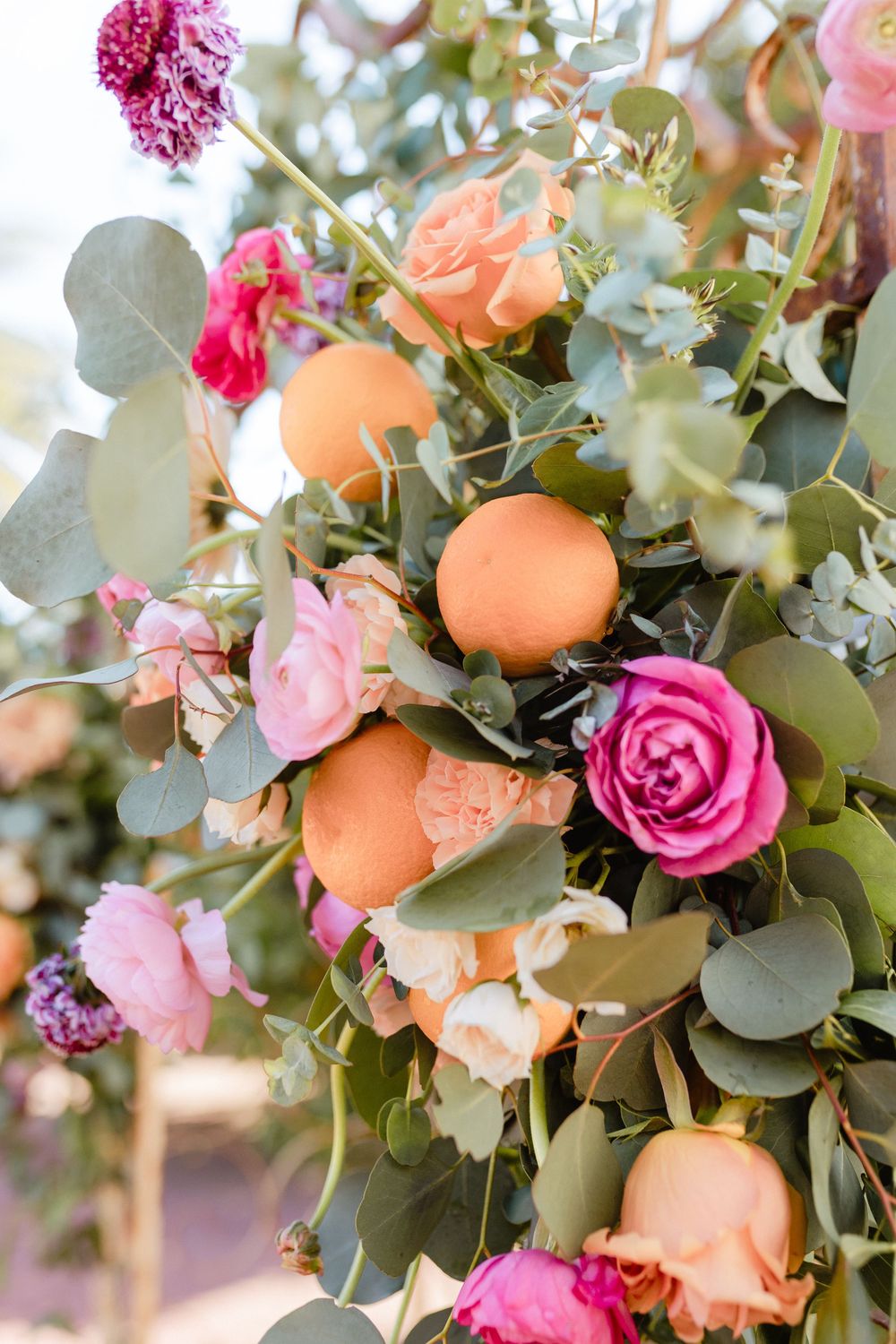 A romantic floral arrangement with peach roses, pink roses, and eucalyptus leaves in a soft, dreamy garden setting.