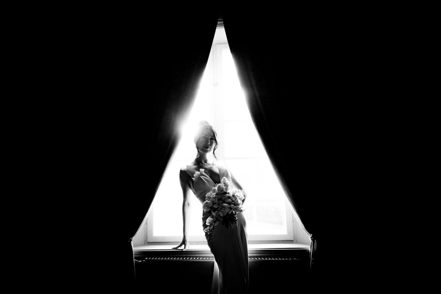 A silhouetted figure stands in front of a bright triangular light source in dramatic black and white contrast.