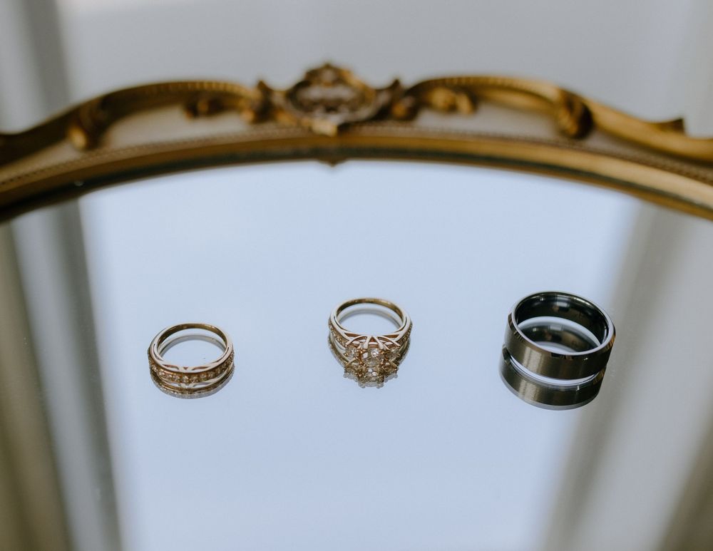 Three elegant rings displayed on a white surface with a decorative gold frame visible at the top of the image.