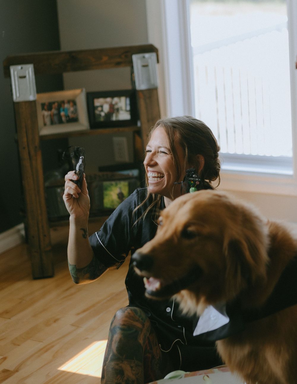 Two friends sharing a laugh while listening to music through earbuds with a brown dog in a bowtie beside them.