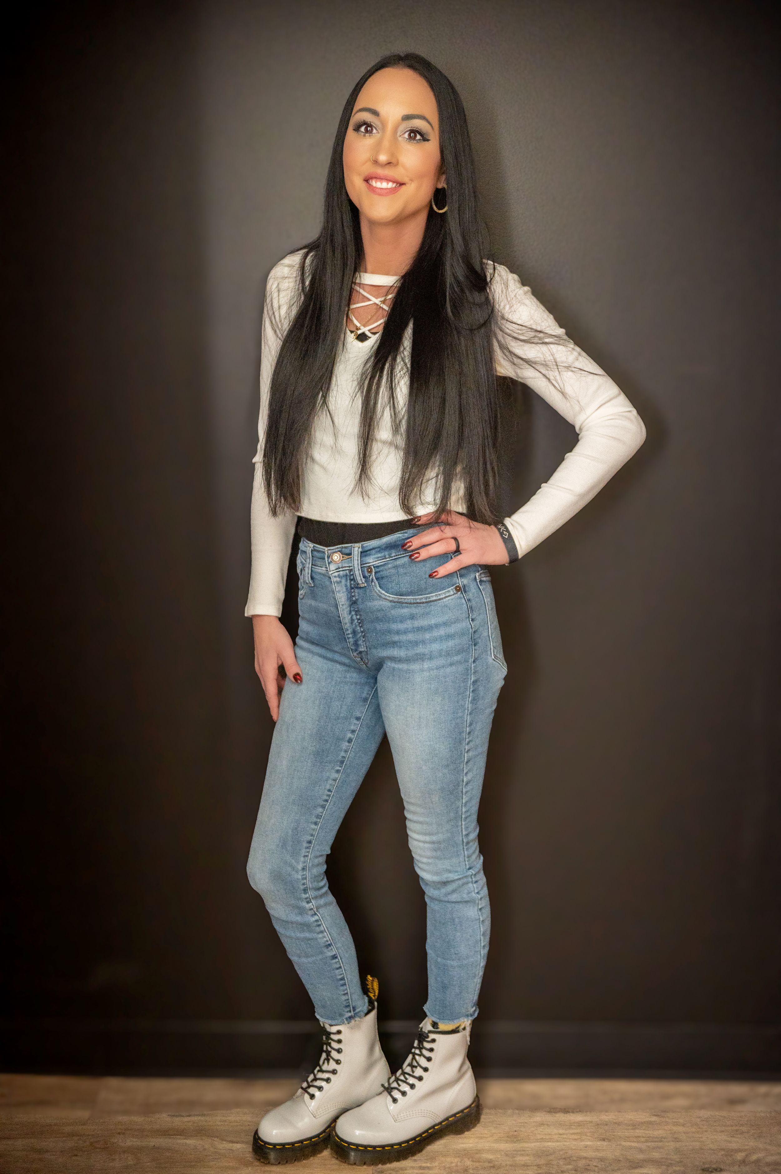A casual fashion photo shoot against a dark background with white combat boots.
