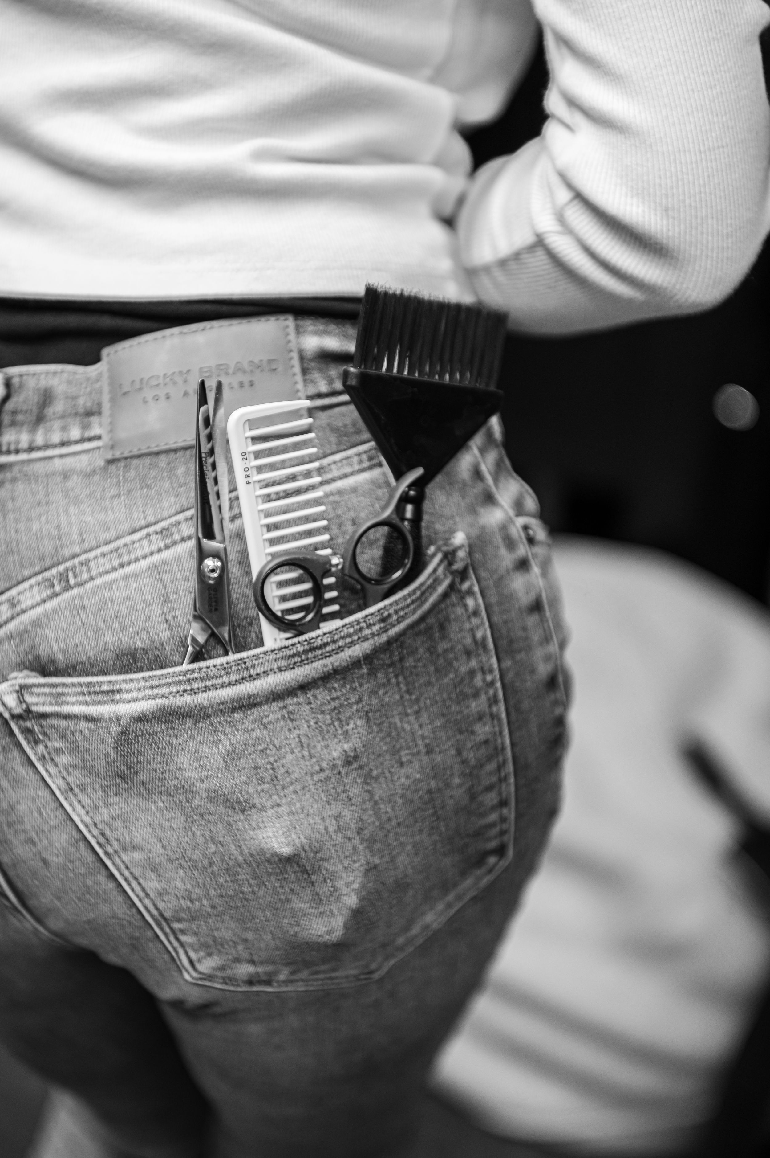 Black and white detail shot of styling tools in back pocket of jeans.