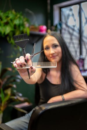 Stylist displays hair cutting tools and combs in professional salon setting.