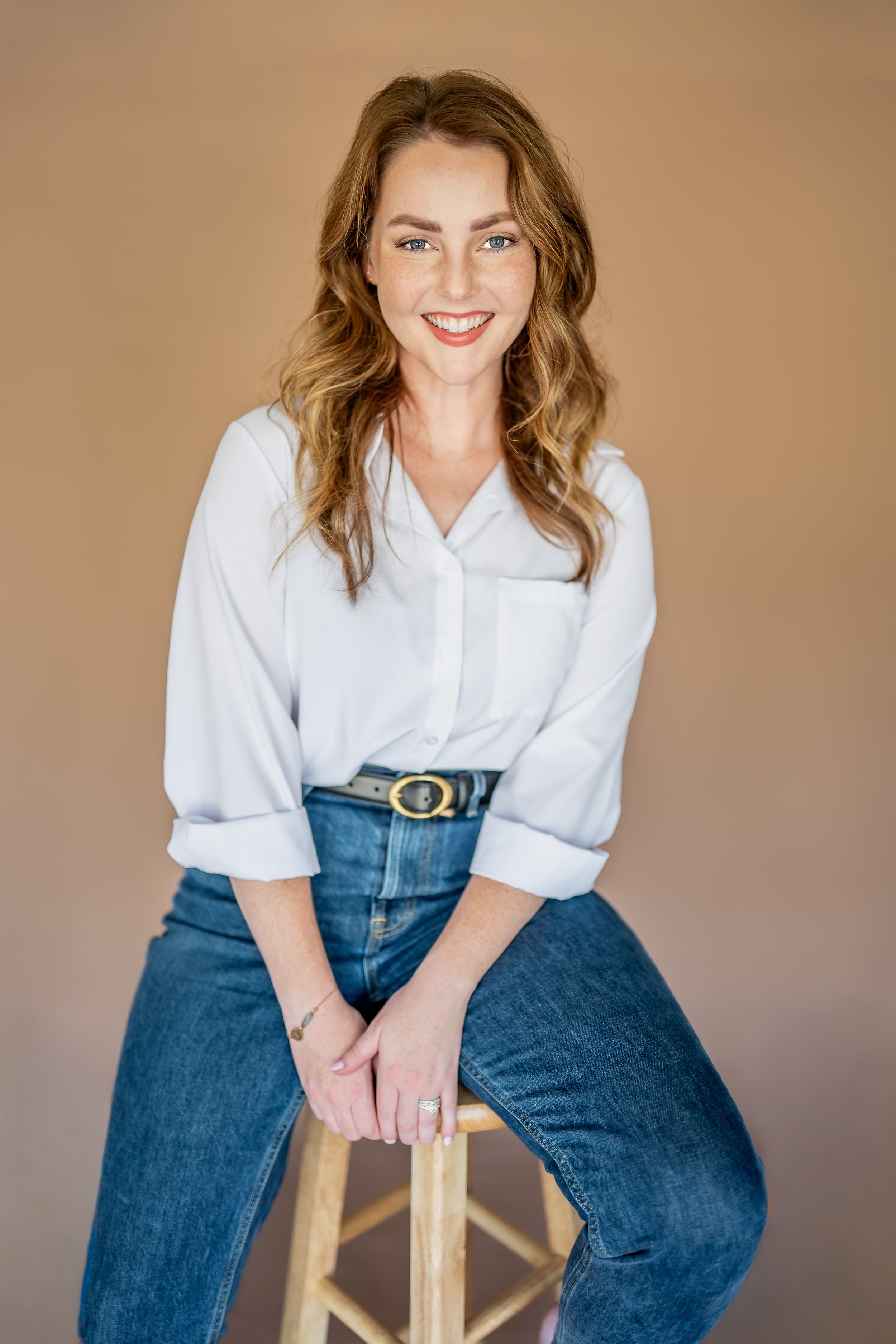 A casual portrait series showing relaxed poses on a wooden stool against a neutral backdrop wearing jeans and white shirt.