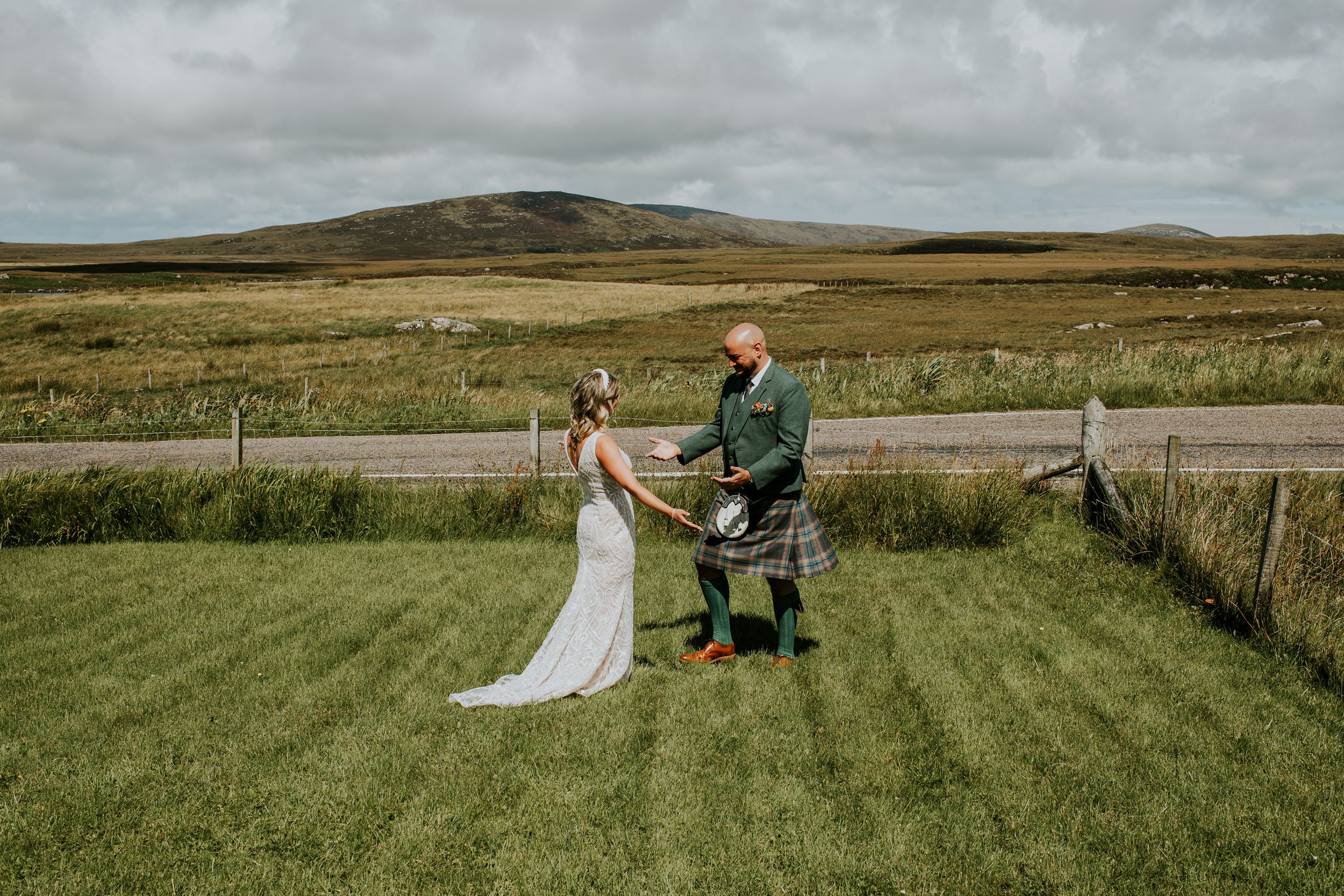 A traditional Scottish wedding celebration on rolling green hills with moody cloudy skies in the background.
