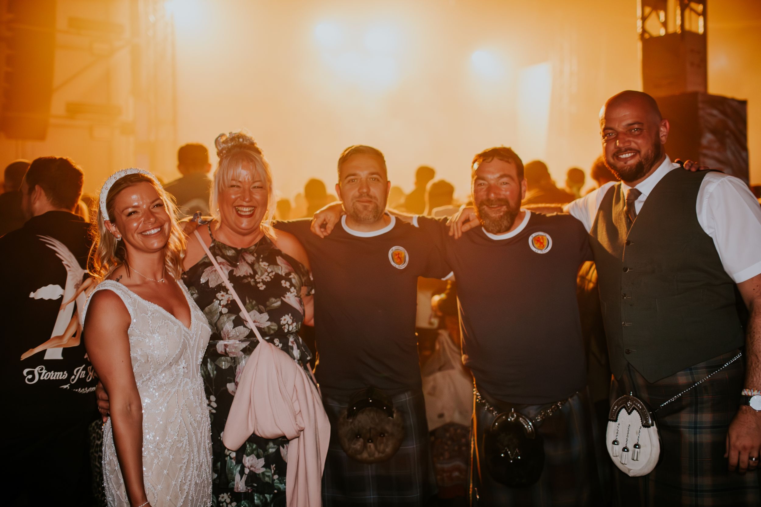 Group celebrates at wedding reception with warm lighting and festive atmosphere.