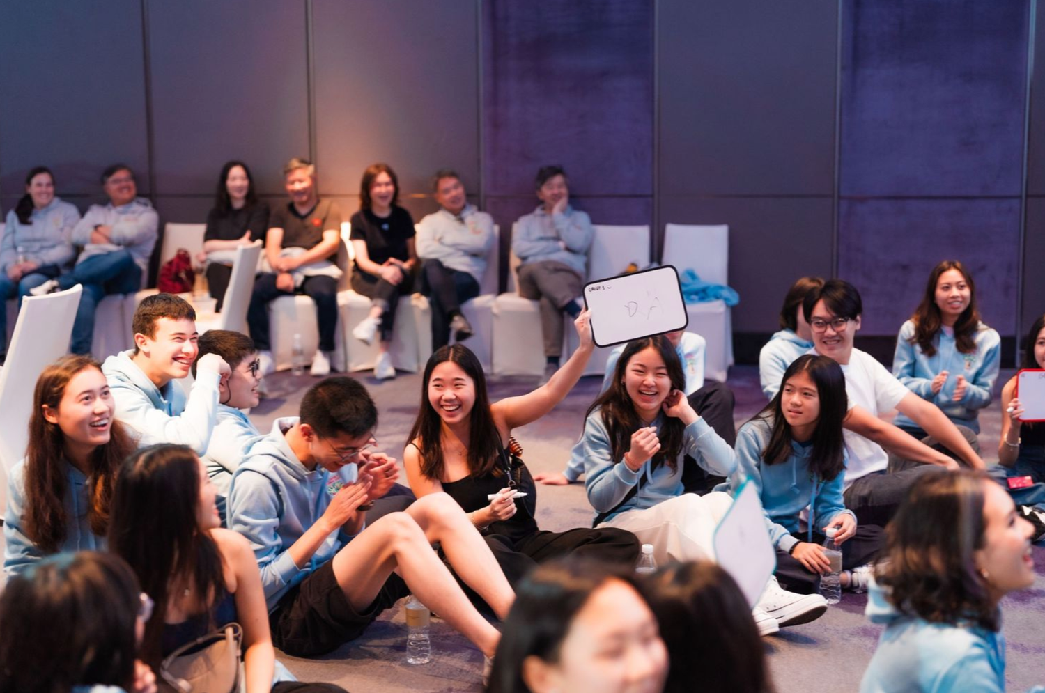 Students sit in a casual lecture hall setting during a group discussion or interactive class session.