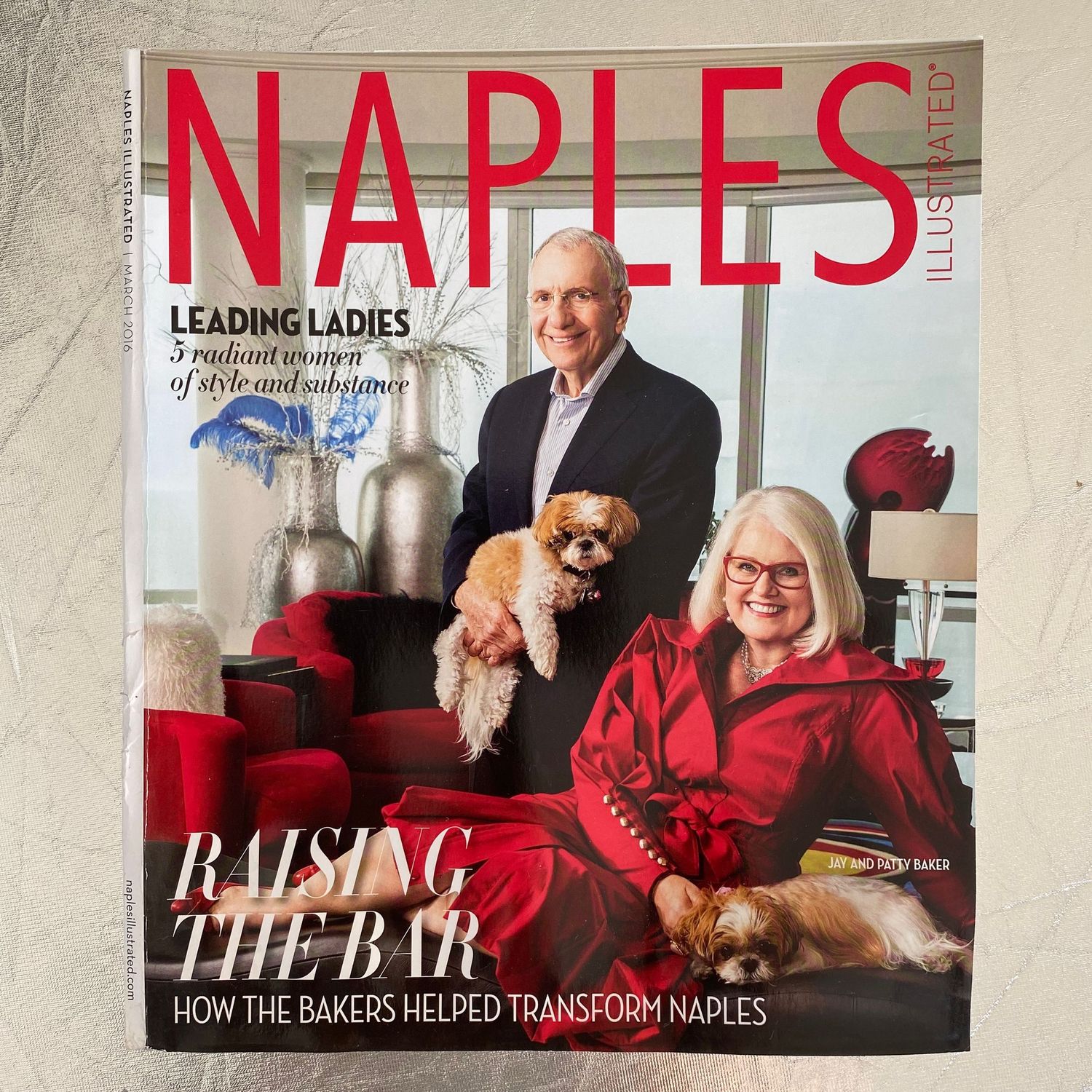 Naples Illustrated Raising the Bar issue featuring couple with small dogs on cover in red setting.