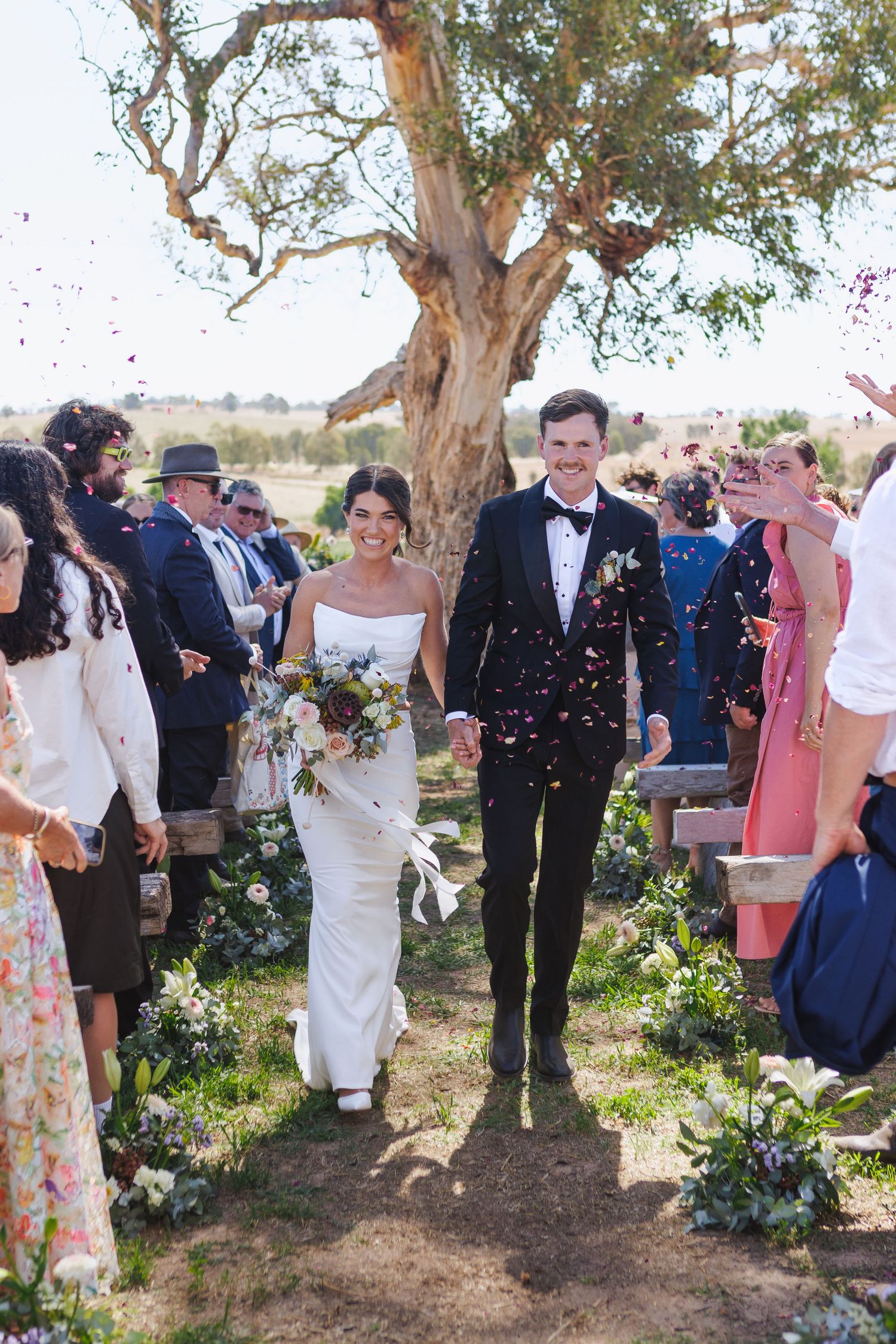 Bride and groom walking down the aisle at country NSW wedding with petals thrown in the air