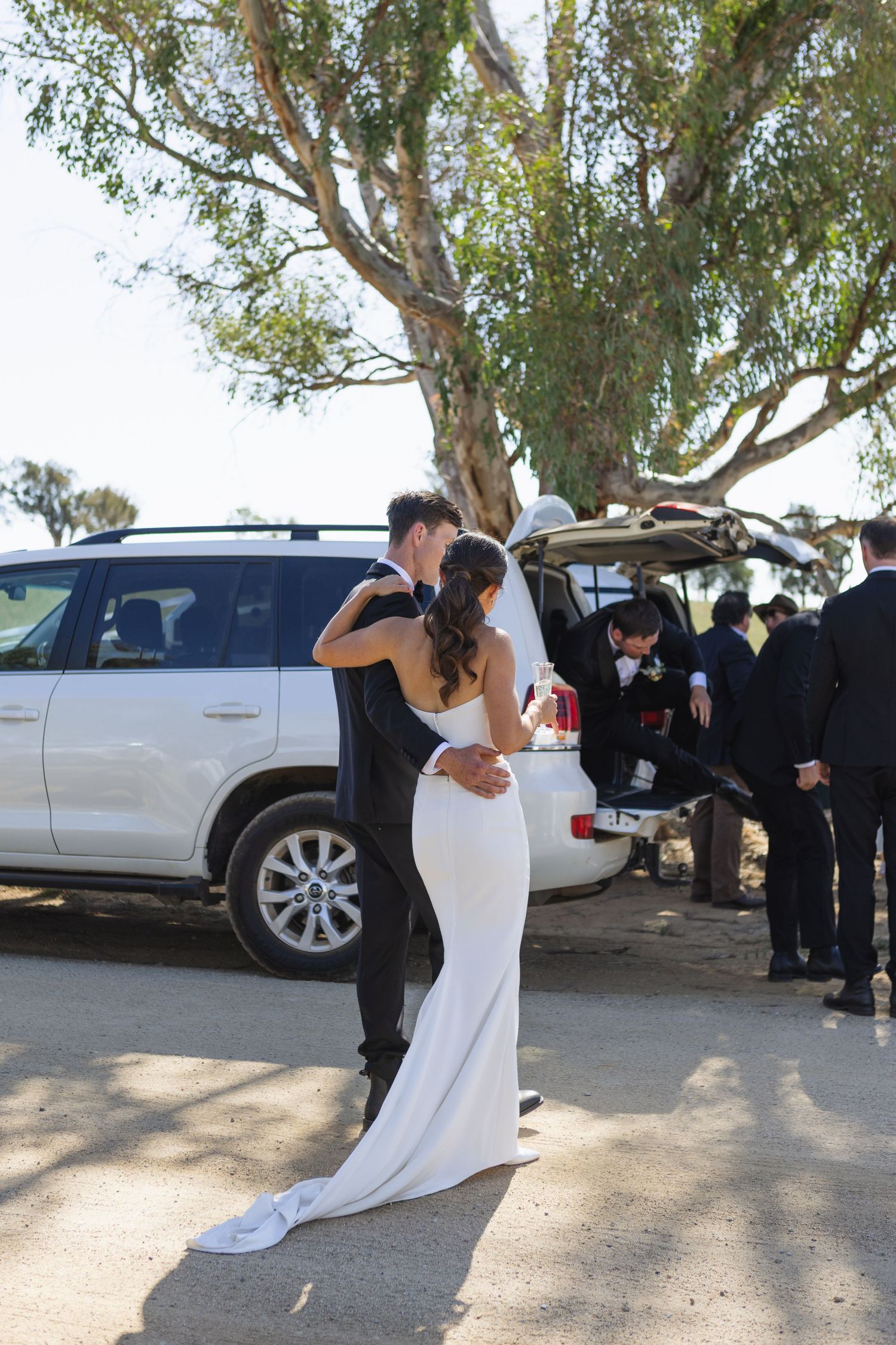 Bride and groom hugging with people in the background at country NSW wedding