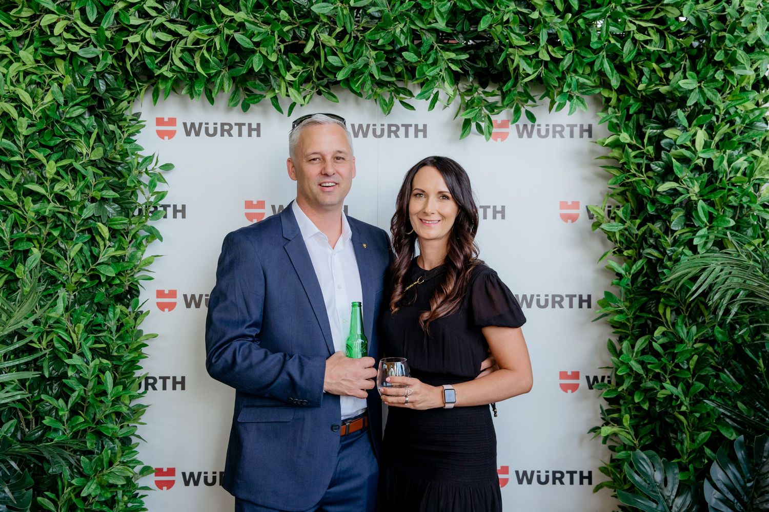 A couple at a corporate event in front of a media wall with company branding