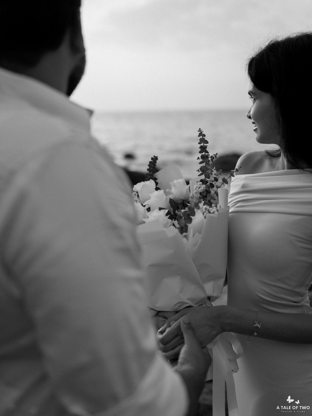A romantic black and white beach scene with flowers and ocean views during a special moment.