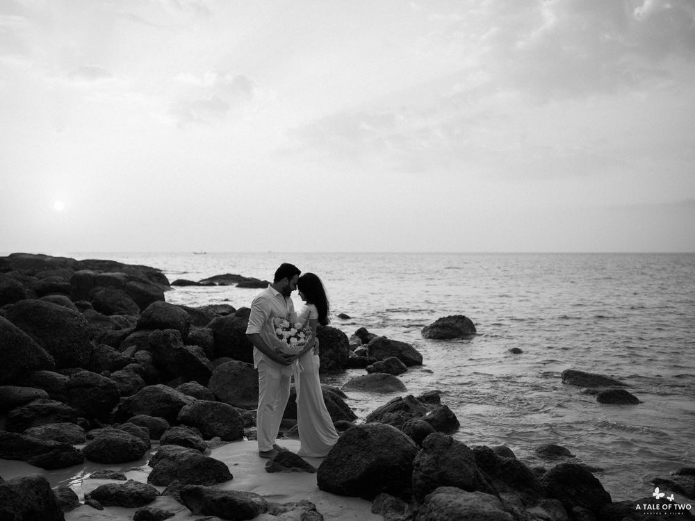 Rocky coastline at sunset with dark boulders against misty ocean horizon.