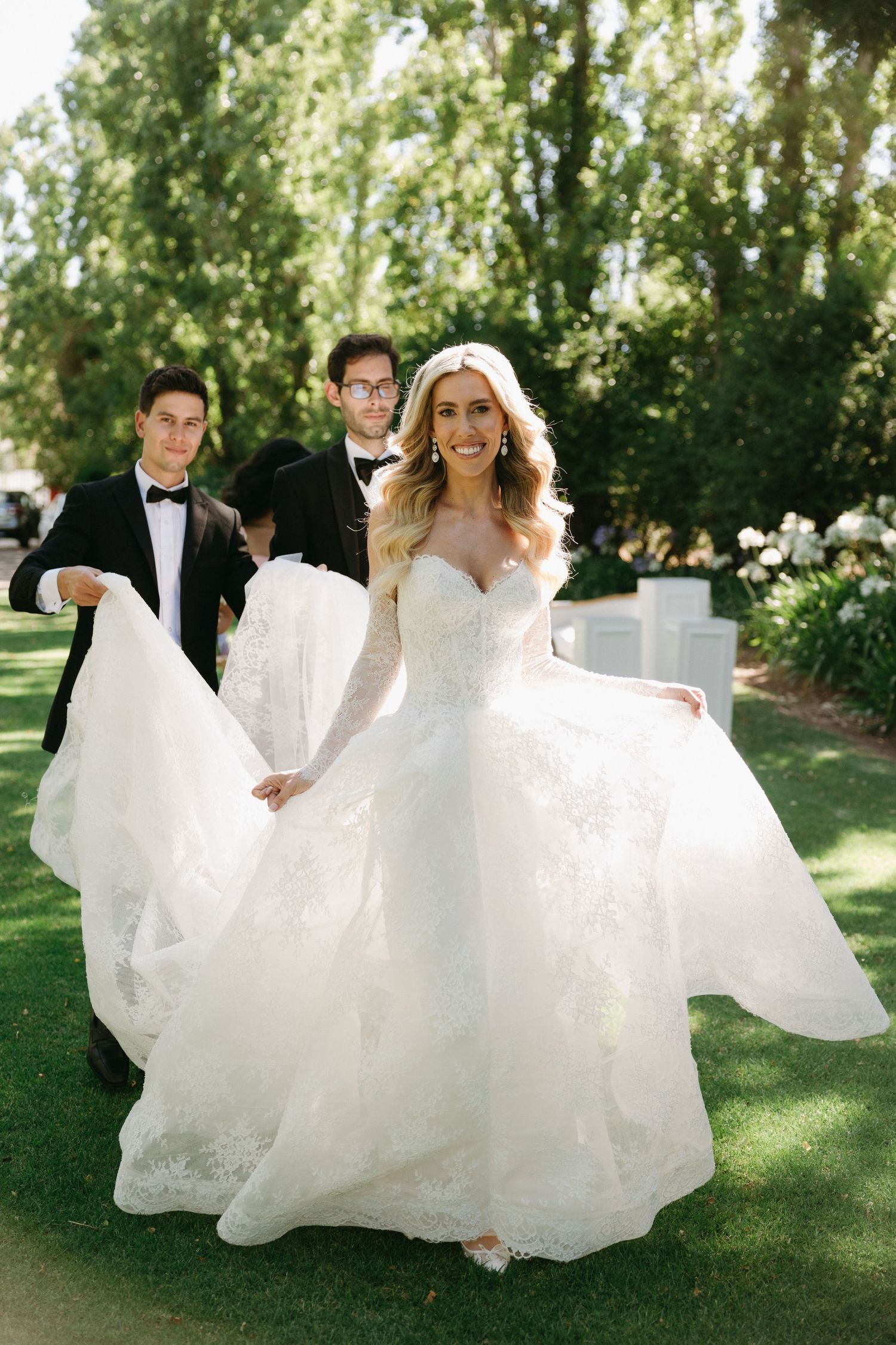 A flowing white wedding gown twirls in a sunlit garden setting.