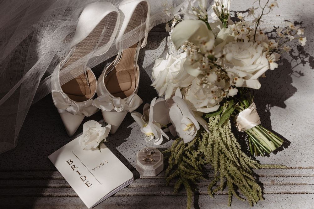 A romantic wedding detail shot showing floral arrangements, place cards, and delicate decor elements in soft neutral tones.