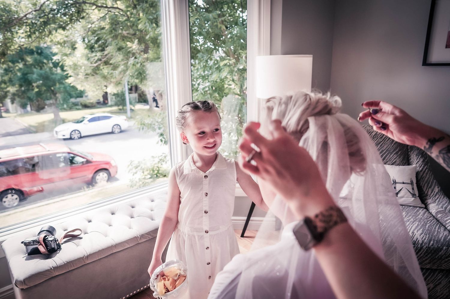 Bride having her hair done during makeup session, a little girl looking on with admiration, Newfoundland wedding.