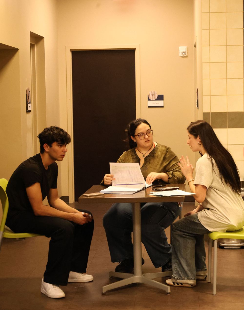 Students studying and collaborating in a minimalist hallway setting with beige walls and floor.